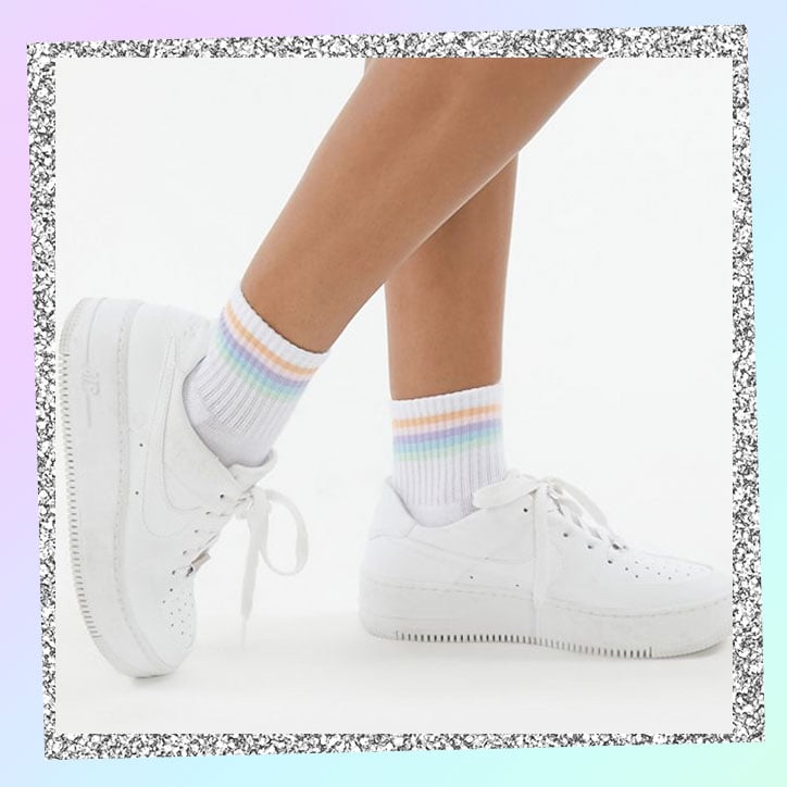 Legs wearing short pastel striped tube socks and white sneakers