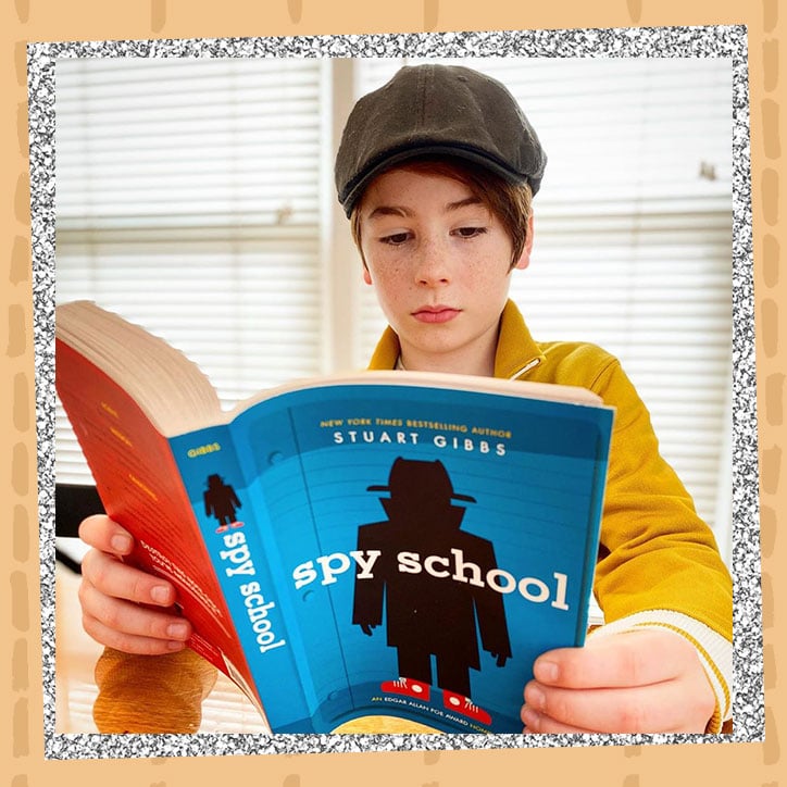 Actor Paxton Booth reading a copy of Spy School by Stuart Gibbs