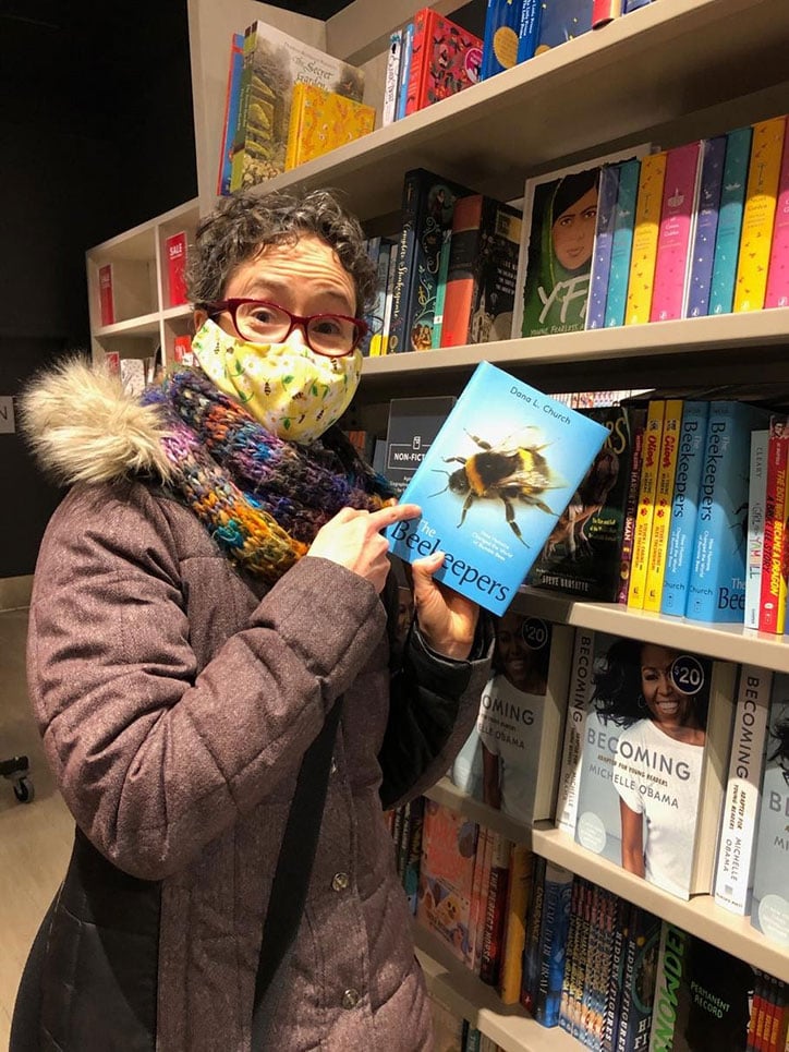 Author Dana L. Church holding a copy of The Beekeepers in a library