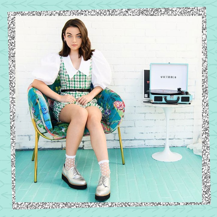 Taegen Burns sitting in a chair next to a record player