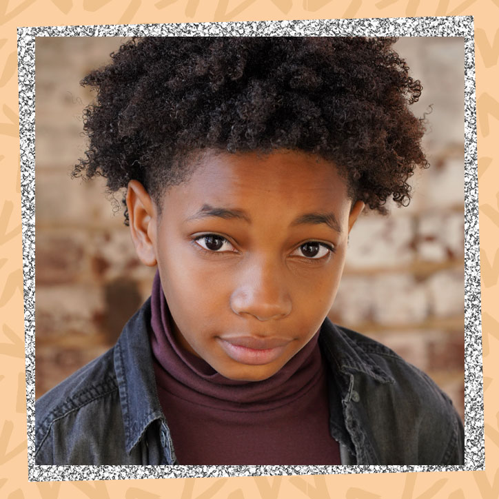 Actor Jecobi Swain poses in front of a brick wall in a black denim jacket