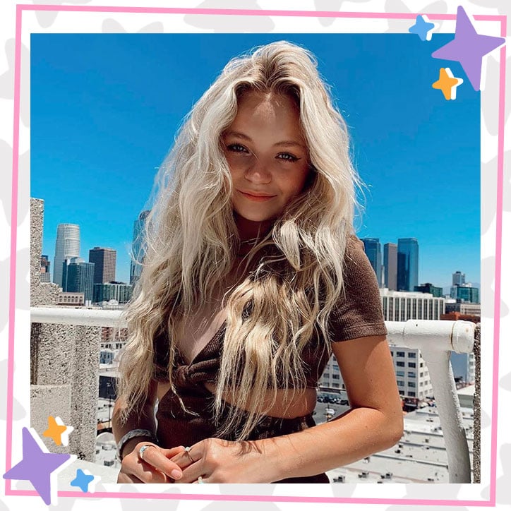 Pressley Hosbach standing on a rooftop with long wavy hair in a brown dress