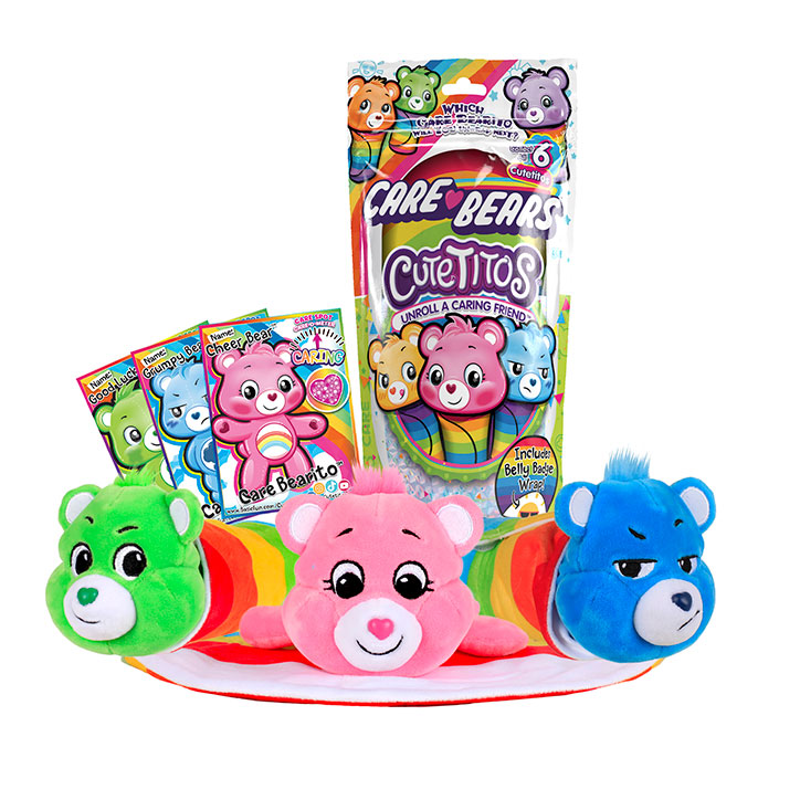 Care Bears Cutetitos Packaging with Cheer Bear, Grumpy Bear, and Good Luck bear laying in front on top of one of their belly badge wraps. Image also shows character cards for each of the three characters shown. 