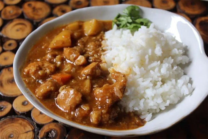 A bowl of Japanese curry with chicken, vegetables, and white rice