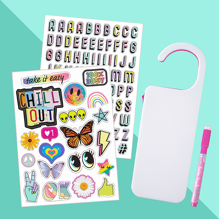 Flat lay of the Fashion Angels Light Up Door Hanger Kit including two sticker sheets, a dry erase marker, and the door hanger