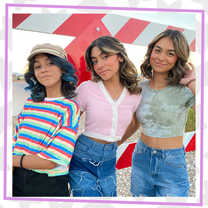 GEM Sisters Evangeline, Mercedes, and Giselle posing together in front of a construction zone