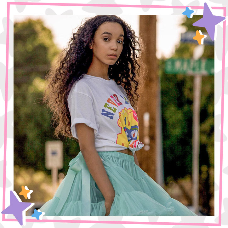 Kherrington Briggs poses outdoors in a baggy white t-shirt and fluffy teal tutu