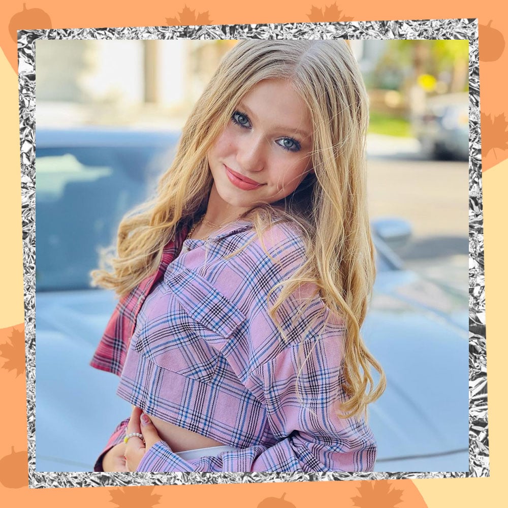 Abigail Zoe Lewis poses in a cropped plaid baby pink jacket with her long blonde hair flowing over her shoulders