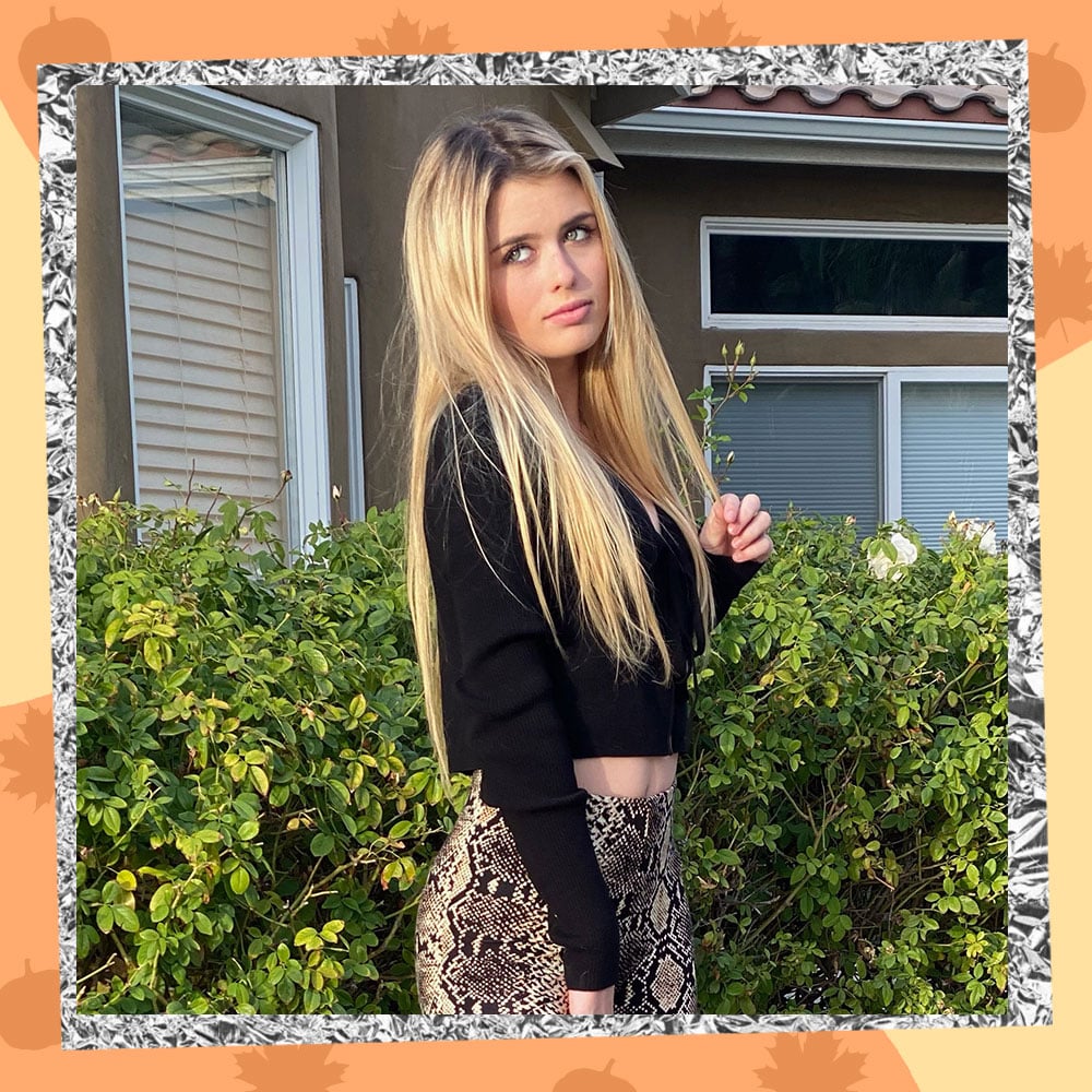 Ruby Lightfoot poses in front of her house with long blonde hair, a cropped black cardigan, and snake print leggings