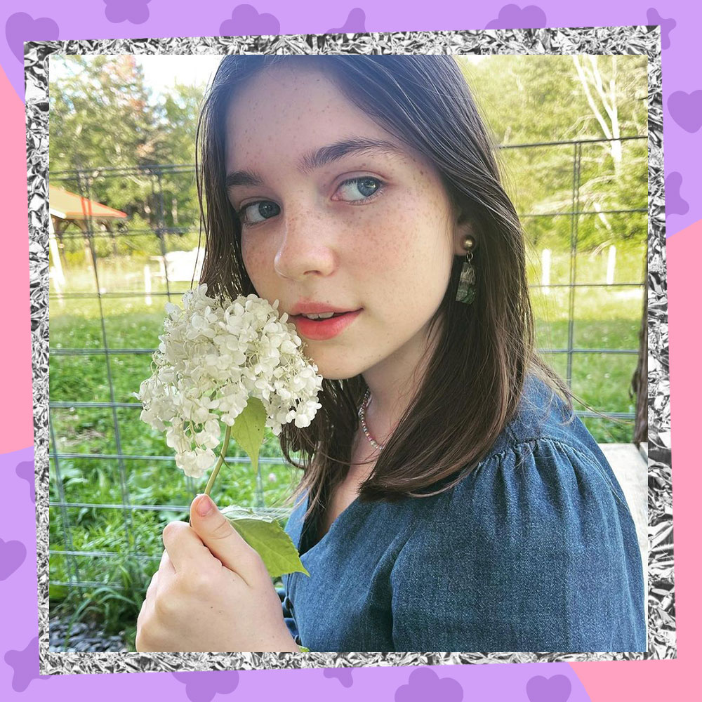 Alexa Swinton poses in a chambray dress while holding a handful of white flowers