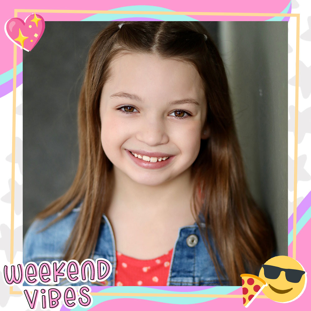 Closeup of Dalya Knapp smiling big, long brown hair in small pigtails, wearing a denim jacket over a red and white polkadot shirt