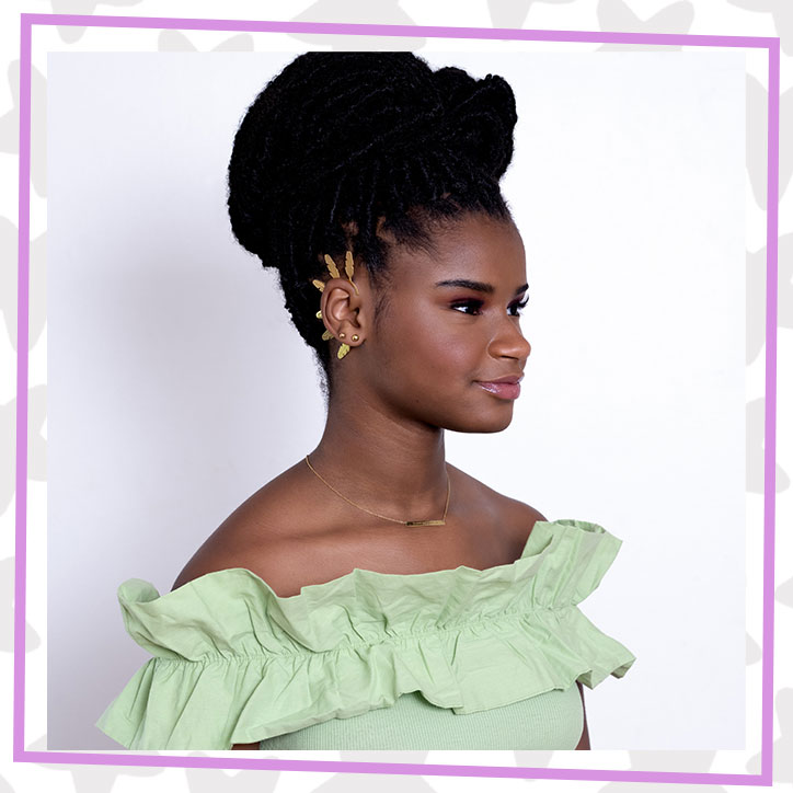 Marley Dias poses in a ruffly mint green dress with her hair in an updo and is turned to the side to show off a gold spiked ear cuff