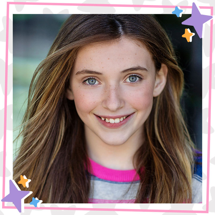 Closeup of Kira McClure smiling, long hair flowing, wearing a rainbow striped sweater