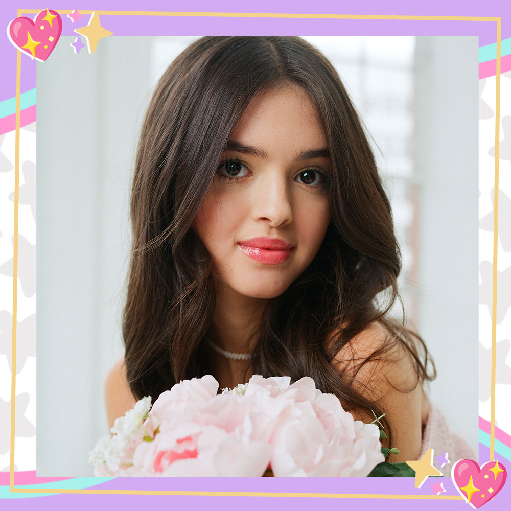 Closeup of Adriana Camposano in a baby pink top holding peonies