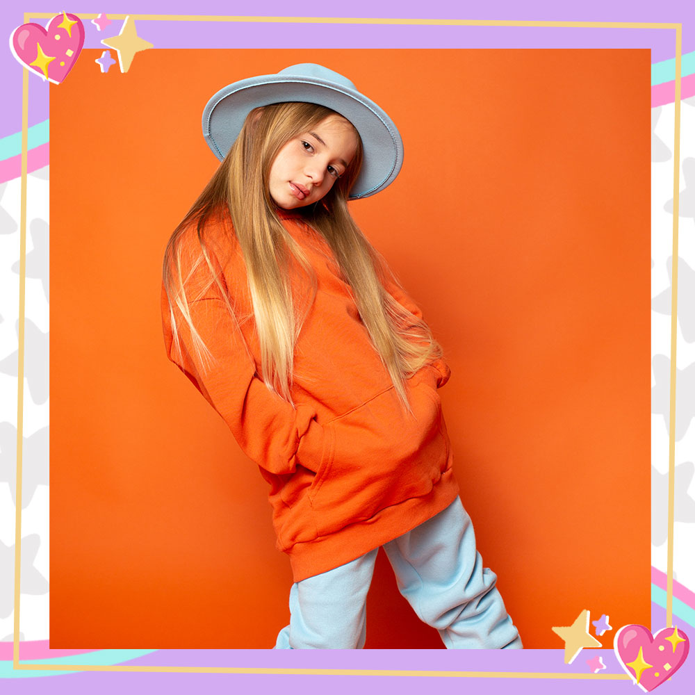 Mandy Corrente posing for the "Super Duper" single cover. She wears a baby blue hat, orange sweatshirt, baby blue sweatpants, and sneakers with her signature bandana tied around her ankle.