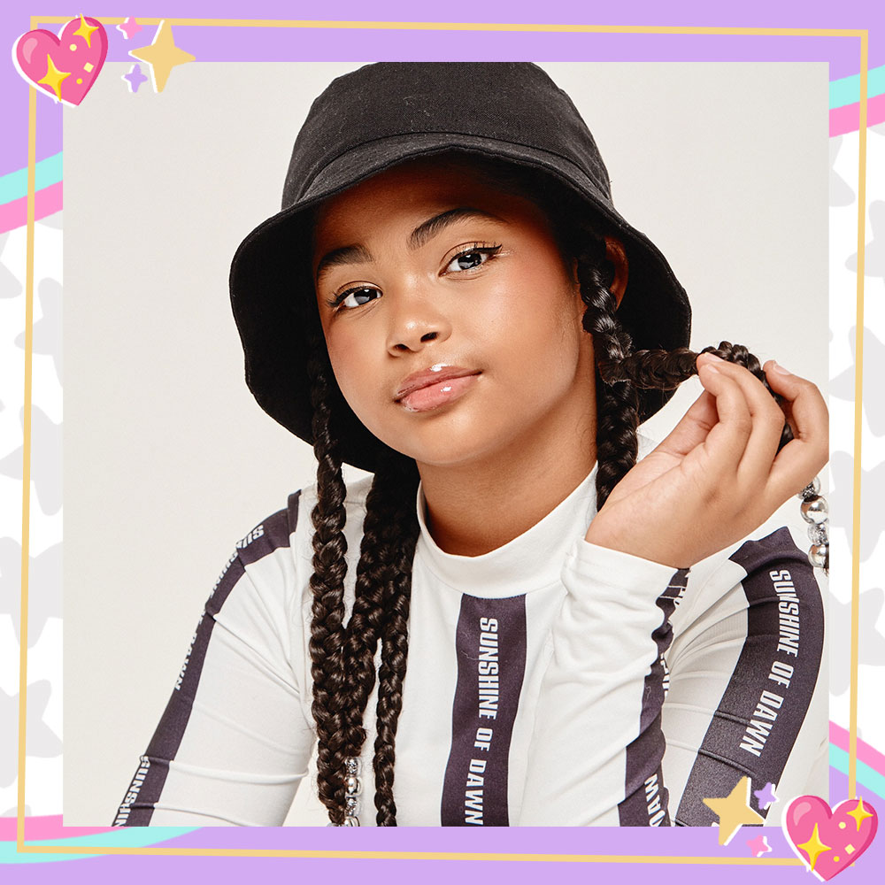 Jaidyn Triplett in a black bucket hair, long braids, and a sport black and white long sleeve shirt.