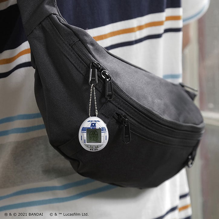 Lifestyle photo of the Star Wars R2-D2 Tamagotchi hanging from a crossbody shoulder bag.
