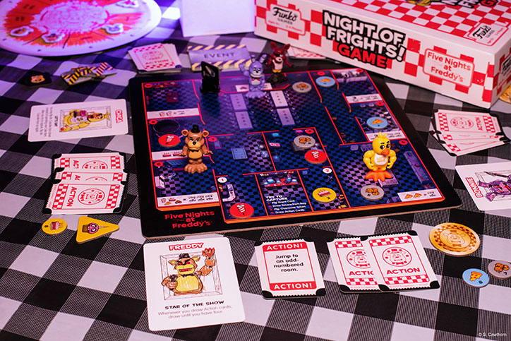 Lifestyle photo of the Five Nights at Freddys Night of Frights Game laid out on a checkered tablecloth, showing off the game board, cards, and other game items