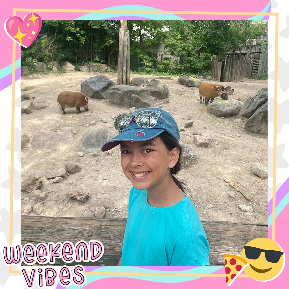 Joselyn Picard poses in front of a warthog habitat at a zoo