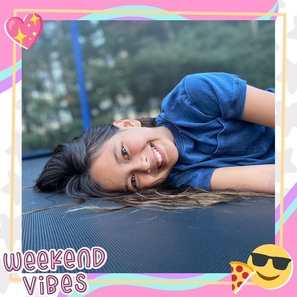 Joselyn Picard laying on a large trampoline, smiling at the camera