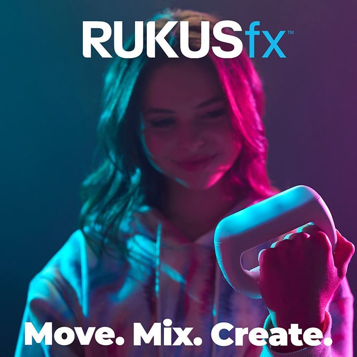 Teen girl holding a RUKUSfx device in a room with pink, purple, and blue ambient lighting