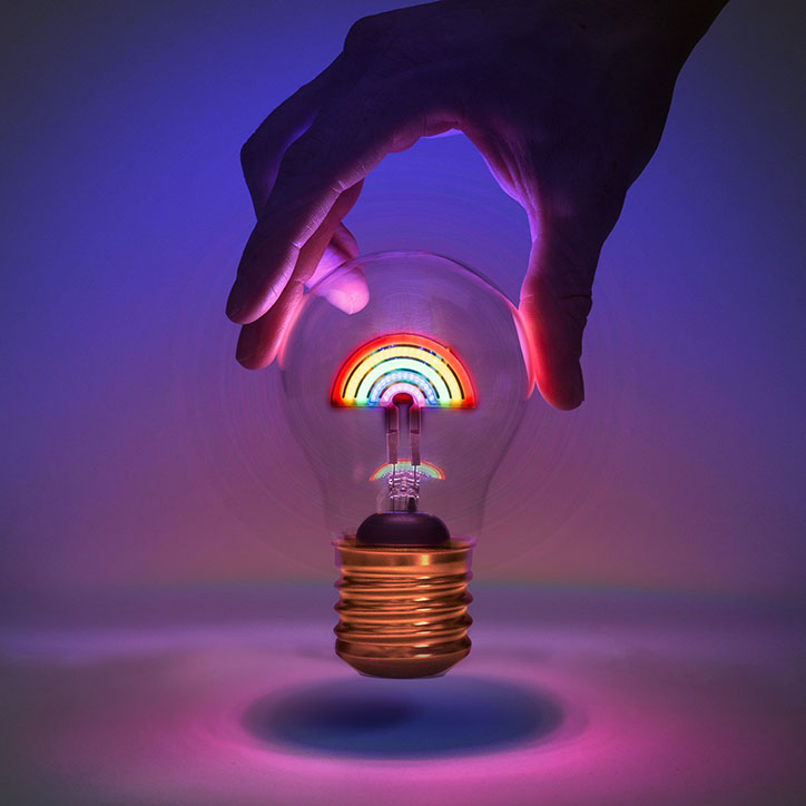 Light-bulb shaped cordless light with glowing rainbow-shaped fillament
