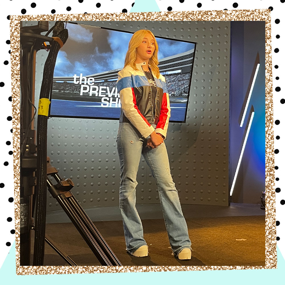 Lacey Caroline in a NASCAR jacket on set as a kid reporter