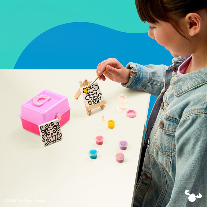 A tween girl sitting at table painting a tiny canvas from a Real Littles Micro Craft kits