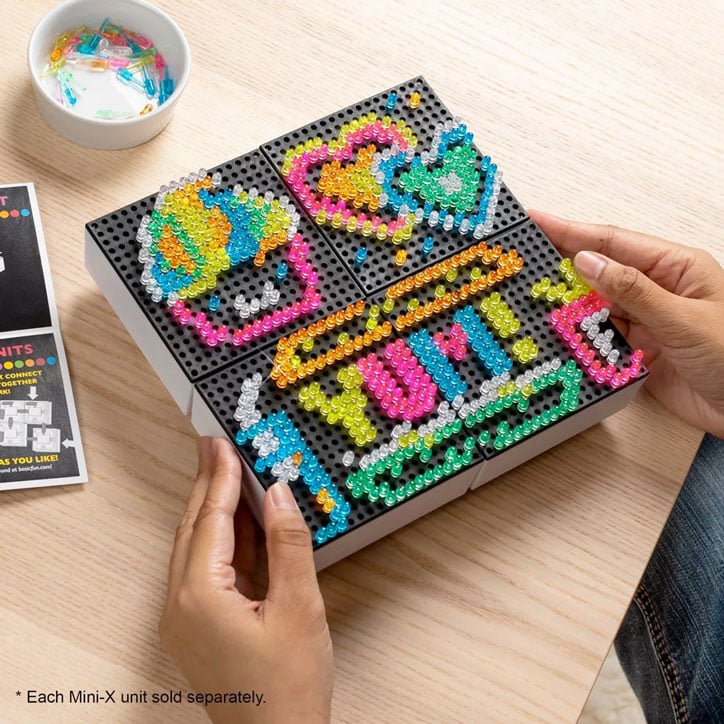 Four Lite-Brite Mini-X Connect devices attached to create a large square canvas. Designs include a smiling cupcake, colorful hearts, and a burger, fries, and drink that says YUM!