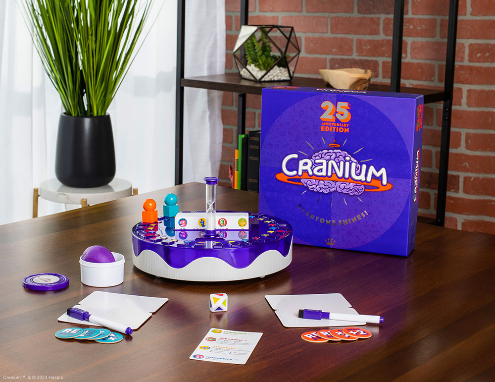 Cranium 25th Anniversary Edition Game box, dry-erase boards, Cranium clay, and other game pieces laid out on a living room table.