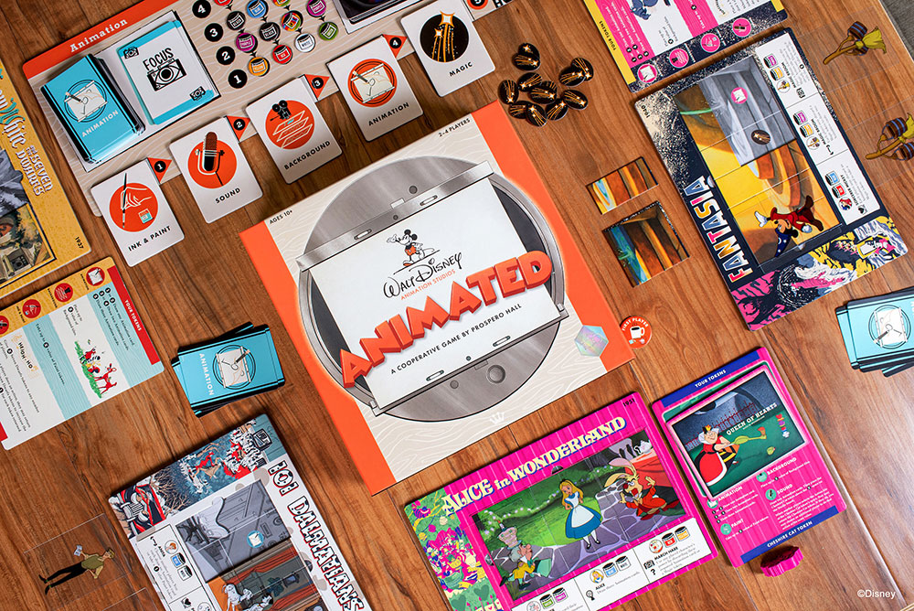 Flat lay of the Disney Animated game. The game box is laid on a hardwood floor surrounded by gameplay elements including game pieces, game boards, tokens, and cards.