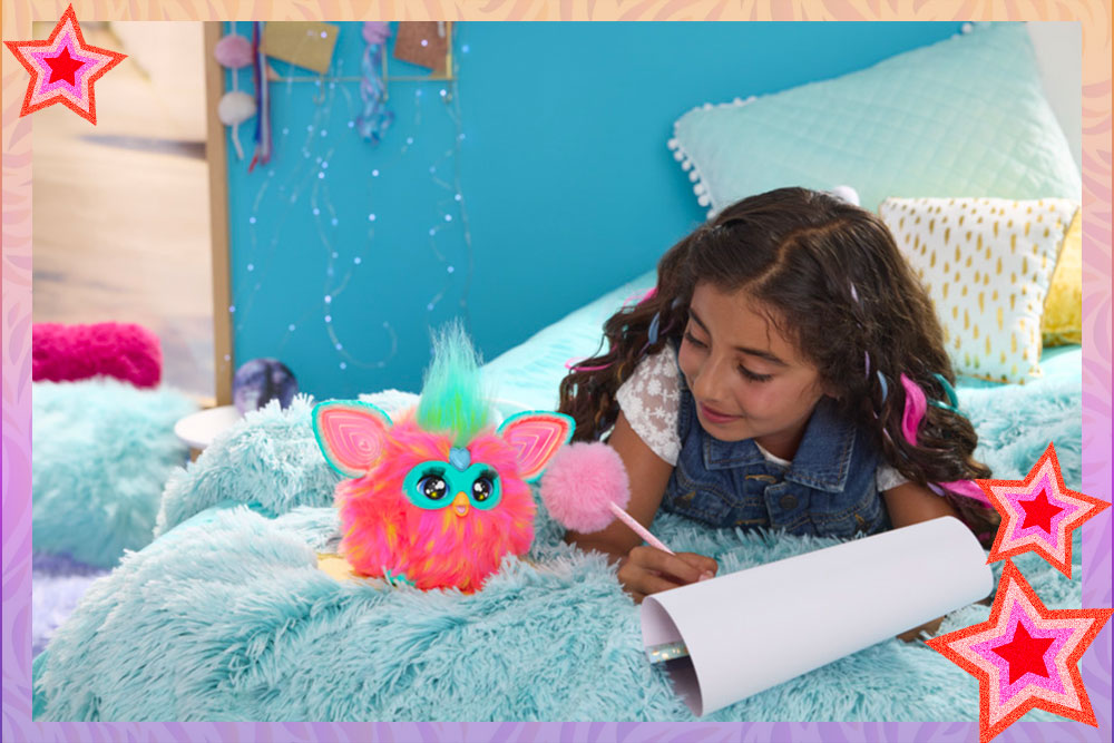 A tween girl laying on a fluffy blanket while writing with a puffball topped pen. A coral Furby sits next to her.