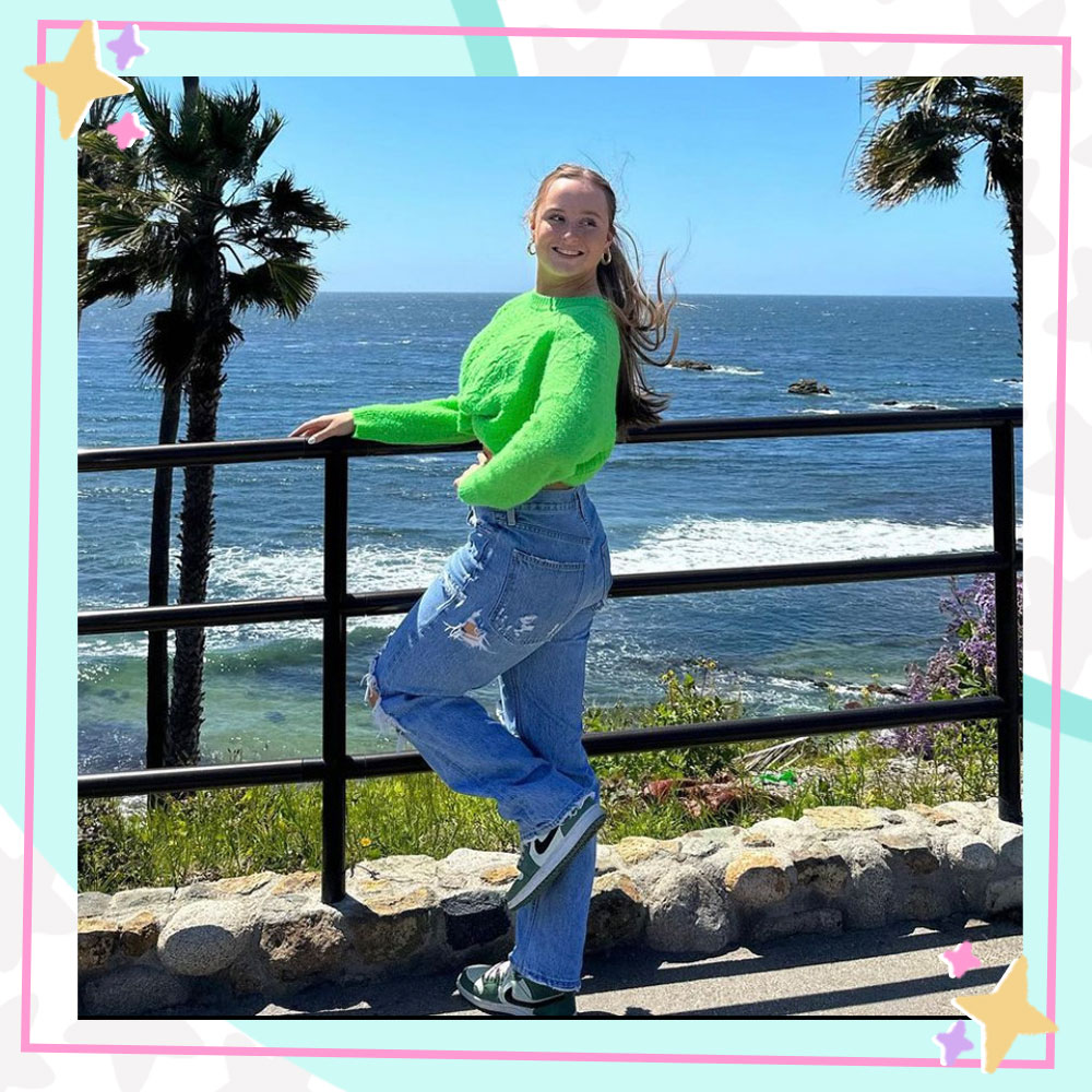 Mackenzie Couch posing by a railing overlooking the beach.