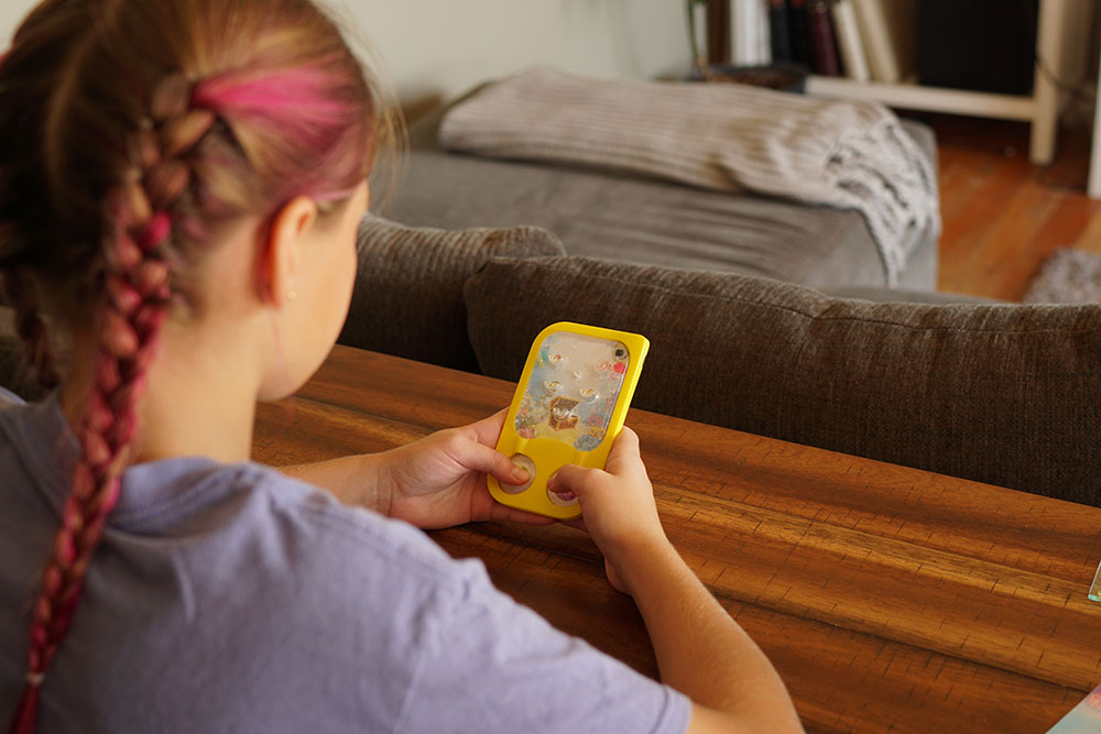 A girl sitting in a living room playing with a GooGames water game