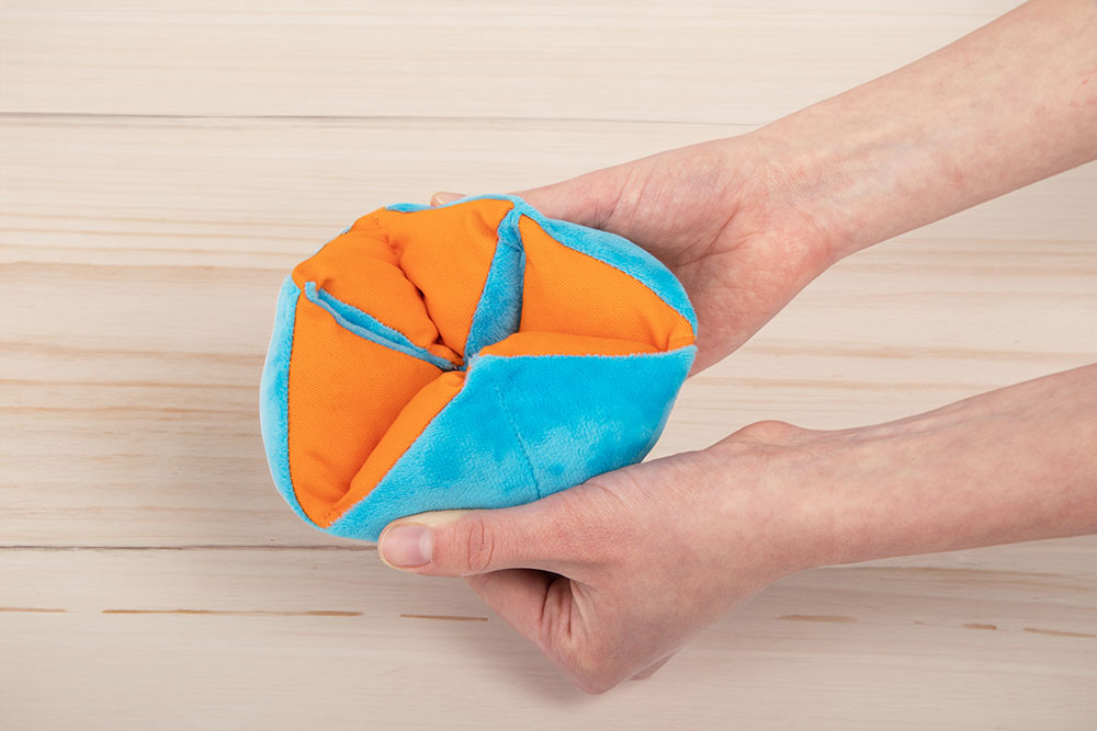 A person holding an Infinity Flipper weighted plush fidget toy