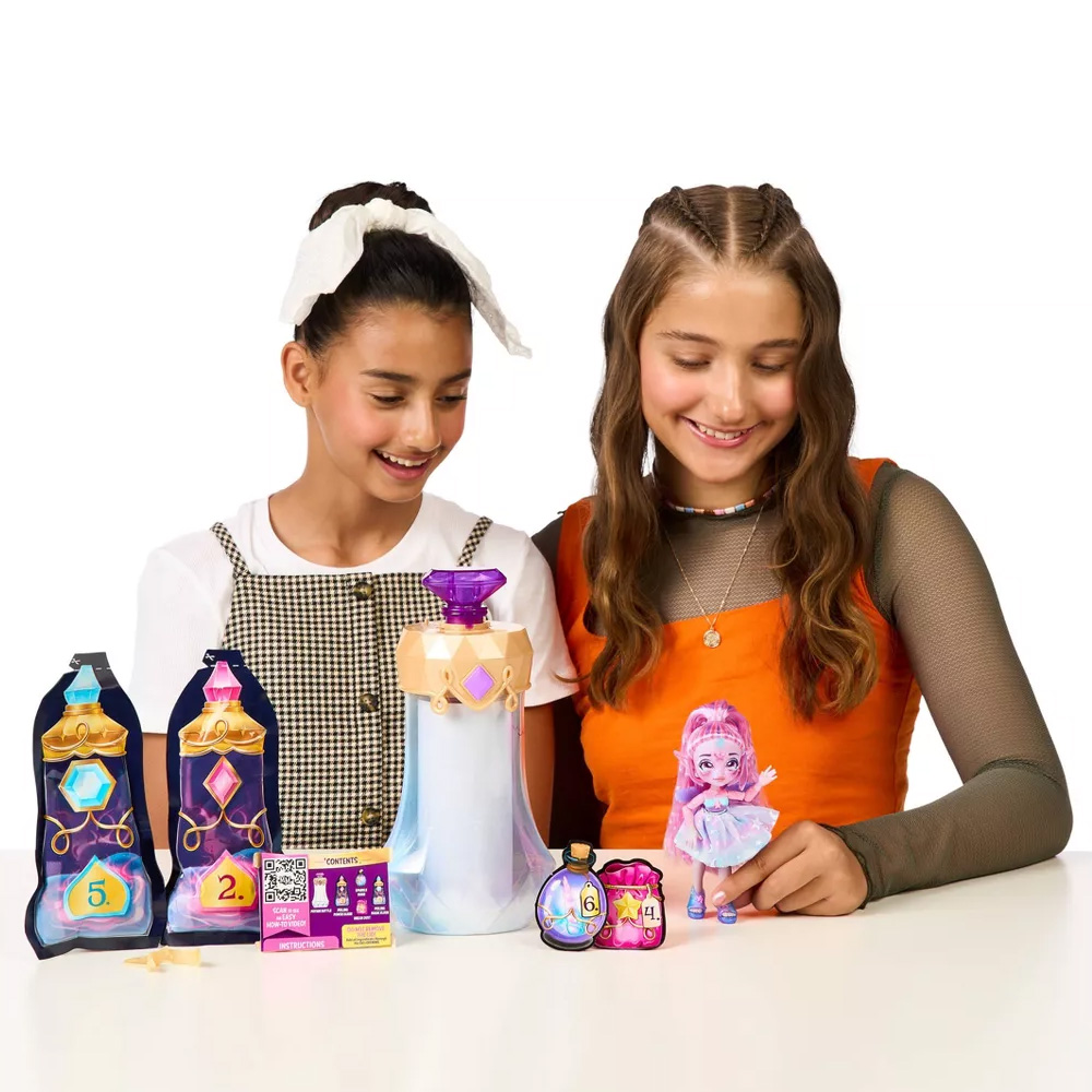 Two tween girls sit at a table brewing their Magic Mixies Pixlings potion to reveal the doll inside