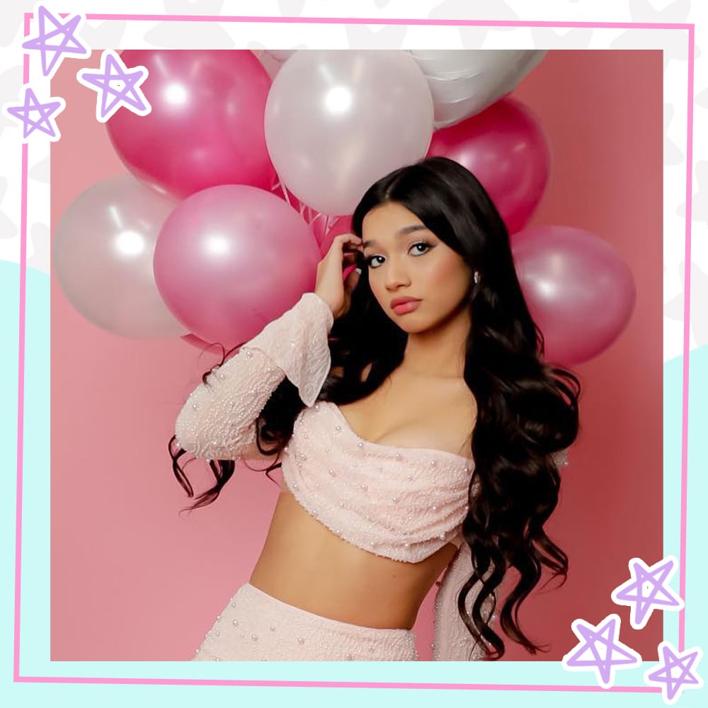 Jasmine Mir poses in a two piece baby pink dress in front of pink and white balloons
